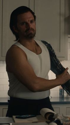 a man in white shirt holding a pair of gloves on top of a kitchen counter