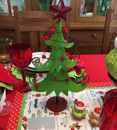 a christmas tree is sitting on a table with red glasses and other holiday decorations around it