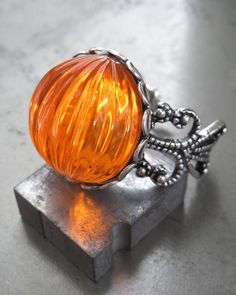 "Retro and so much fun -- bright, neon orange pumpkin ring for Halloween! This brilliant orange ribbed acrylic vintage cabochon has incredible visual depth -- it reflects light as if it were glowing! The vintage flatback cabochon is set in a antiqued silver bezel on a deluxe, sturdy decorative gothic filigree adjustable ring band. The ring fits approx. size 6 to 9. - Vintage acrylic orange cabochon: 3/4\" (18mm) dia, 1/2\" (12mm) tall - Sturdy, thick antiqued silver filigree ring: adjustable fro Ring Trick, Pumpkin Ring, Pumpkin Jewelry, Orange Cocktails, Halloween Ring, Orange Ring, Pumpkin Gift, Orange You Glad, Gothic Rings