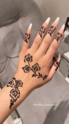 a woman's hand with black henna tattoos on her left wrist and fingers