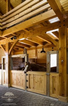 the inside of a horse barn with wooden stalls