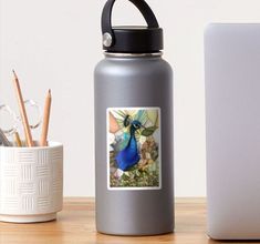 a blue bird sitting on top of a wooden table next to a cup and pencils