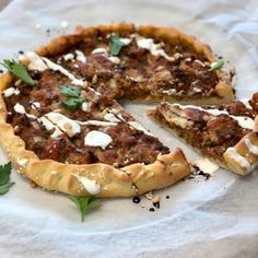 a pizza sitting on top of a piece of paper with cheese and herbs around it