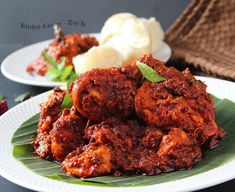 some food is on a white plate with green leafy leaves and another dish in the background