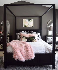 a black and white bedroom with pink fur rugs on the floor, four poster bed