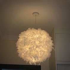 a chandelier hanging from the ceiling in a room with white cabinets and cupboards