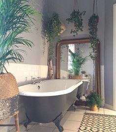 a bath tub sitting next to a mirror and potted plants on the wall in a bathroom