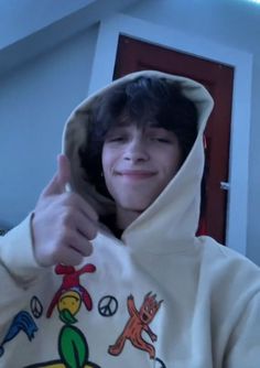 a young man wearing a hoodie giving the thumbs up