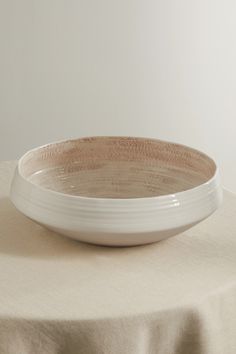 a white plate sitting on top of a table next to a beige cloth covered tablecloth