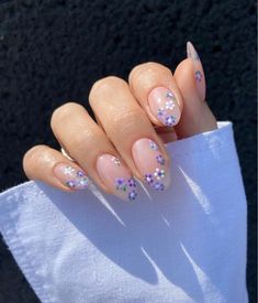 a woman's hand with some pink and purple nail polishes on her nails