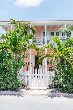 a pink house with white picket fence and palm trees