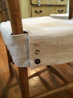 an old fashioned chair with buttons on the seat and linen covering it's back