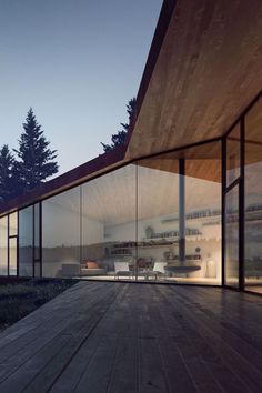 the interior of a house with glass walls and wood flooring is lit up at night