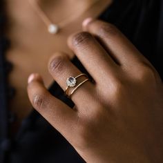 a woman's hand wearing a gold ring with an oval shaped diamond on it