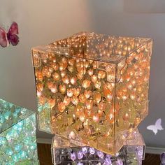 there are many different colored lights in the glass cubes on the table and one is filled with flowers