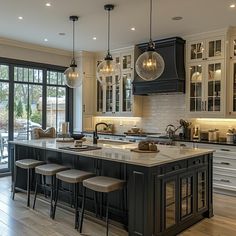 a large kitchen with lots of counter space and lights hanging from the ceiling over the island