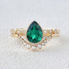 a close up of a ring with a green stone and pearls on the bottom side