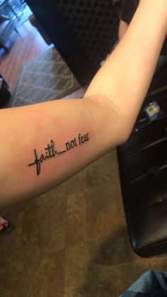 a person with a tattoo on their arm that says faith not fear in cursive writing