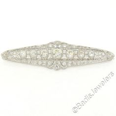 "Here we have a stunning diamond brooch crafted in solid platinum during the art deco period. It features 7 large old European cut diamonds which are bead set in elegantly milgrain-etched octagonal shape baskets. The brooch is then drenched with petite old mine cut diamonds which total approximately 1.20 carats, beautifully accenting this piece along with the finest etching work and filigree designs showcasing the masterful workmanship used during the art deco period. The center diamond is a lar Vintage Platinum Brooches With Diamond Accents, Classic White Diamond Brooches, Classic Platinum Brooches With Diamond Accents, Classic Platinum Brooches, Vintage Platinum White Gold Brooches, Vintage Platinum Brooch In White Gold, Vintage White Gold Platinum Brooches, Art Deco Platinum Brooches For Anniversary, Classic Platinum Brooch For Anniversary