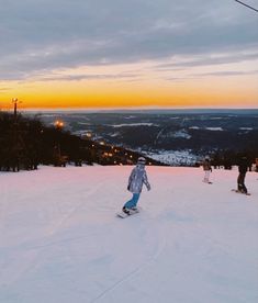 a person riding a snowboard down the side of a snow covered slope at sunset