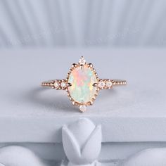 an opal and diamond ring sits on a white surface