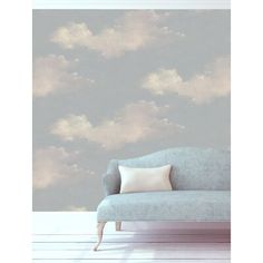 a couch sitting in front of a wall with clouds on it