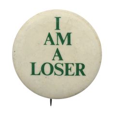 a white button with green lettering that says i am a loser