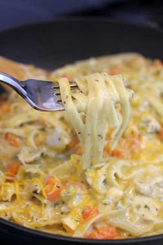 a fork full of noodles and vegetables being lifted from a skillet