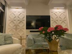 a living room with couches, chairs and a vase full of flowers on the coffee table