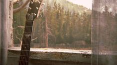 an old guitar sitting in front of a window