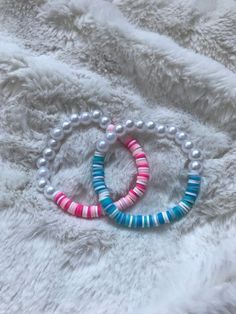 two bracelets with pearls and beads on a white furnishce background, one is pink, the other is blue