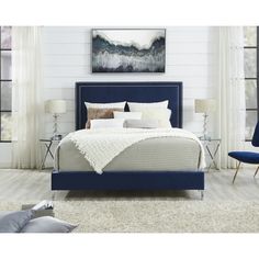 a bed with blue upholstered headboard and foot board in a white room