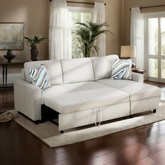 a living room with a white couch and wooden floors in front of two large windows