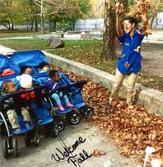 a man standing next to two strollers with children in them and leaves on the ground