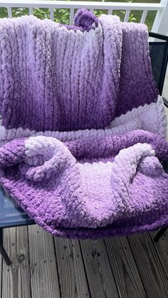 a purple and white blanket sitting on top of a wooden deck next to a chair