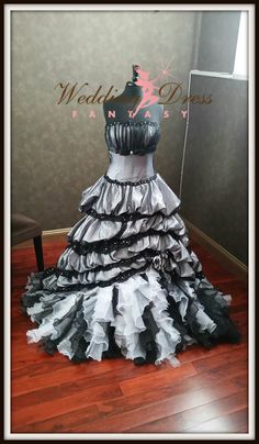 a black and white dress with ruffles on the skirt is sitting in front of a mirror