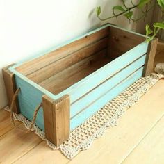 a wooden crate sitting on top of a wooden floor next to a potted plant