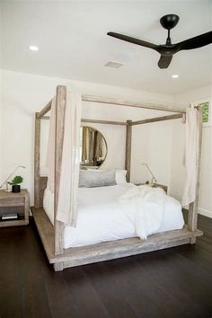 a white bed sitting on top of a hard wood floor next to a ceiling fan