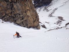 a man riding skis down the side of a snow covered slope next to a mountain