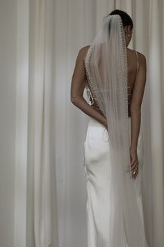 the back of a bride's wedding dress, with her veil draped over her shoulder