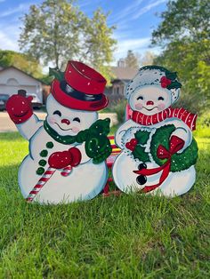 two snowmen are standing in the grass