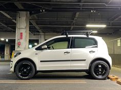 a small white car parked in a parking garage with its roof rack on the door