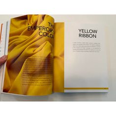 a person is holding an open book with yellow fabric on the cover and in front of it