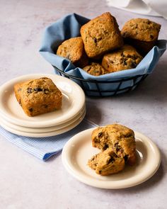 two plates with muffins on them next to a basket of muffins