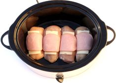 four different colored marshmallows in a crock pot on a white background