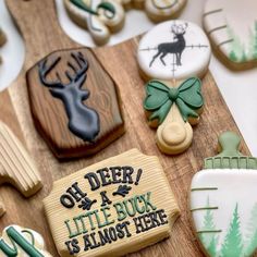 decorated cookies are displayed on a wooden cutting board with green and white frosted decorations