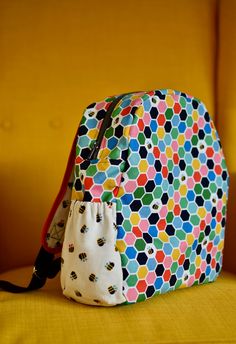 a multicolored backpack sitting on top of a yellow couch next to a wall