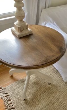 a wooden table sitting on top of a bed next to a white pillow and window