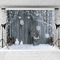 a christmas scene with snowflakes and pine cones on a wooden fence, surrounded by lights