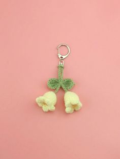 two crocheted poodles hanging from a keychain on a pink background